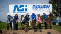 Photo of 8 people in white hard hats shoveling dirt