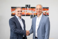 Photo of two men dressed in blue suits shaking hands 