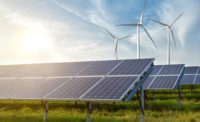 array of solar panels with wind turbines in the background