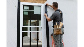 Picture of man on ladder installing tape around door frame