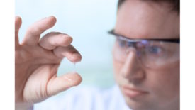 Picture of a scientist holding adhesive glue between his fingers